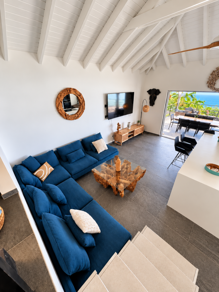 Salon contemporain et lumineux avec haut plafond et canapé bleu à la Villa Sunset Saint-Martin